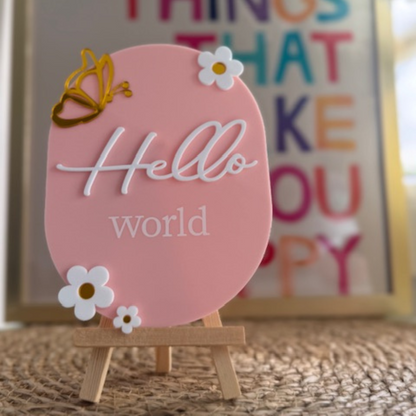 Roze aankondigingsbordje hello world. Kraamcadeau met houten standaard
